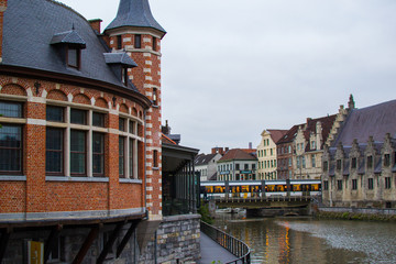 Ghent, Belgium; 10/29/2018: Lys river (Leie) crossing Ghent with a medieval monument on the right