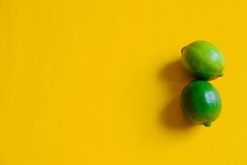 Two green limes against yellow background showing concept of happiness, summer, positivity and  life