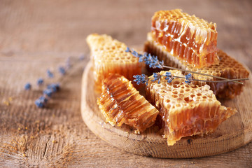 Fresh honeycombs pieces, dry lavender flowers on wooden background. Autumn harvest concept