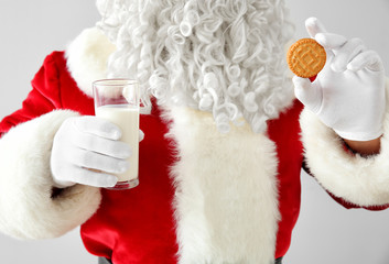Obraz na płótnie Canvas Santa Claus with milk and cookie on light background, closeup