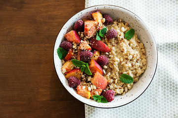 Oatmeal porridge with raspberry and peach on table. Healthy breakfast. Vegetarian food. Top view