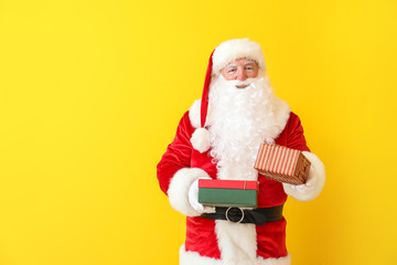 Fototapeta na wymiar Santa Claus with gifts on color background
