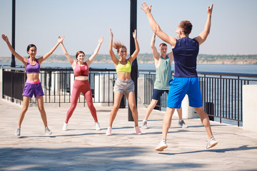 Obraz premium Group of young sporty people training together outdoors