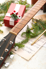 Guitar, note sheets, gift and Christmas decor on table