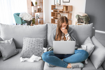 Sick woman working on laptop at home