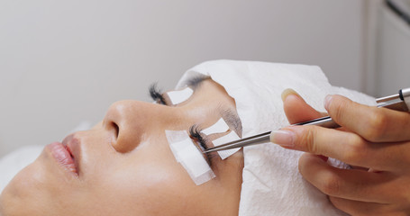 Woman having eyelash extension in beauty salon