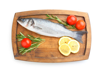 Board with fresh seabass fish, lemon, rosemary and tomatoes on white background