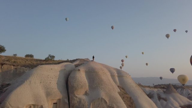 left camera movement show the beautiful ladnscape full of hot air balloons over the Goreme and fairy chimneys city during sunrise