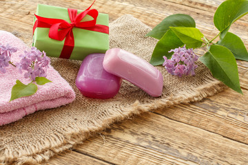 Towel, soap and lilac flowers on wooden background.