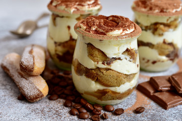 Traditional italian creamy dessert with mascarpone, biscuit and coffee in a vintage jars.