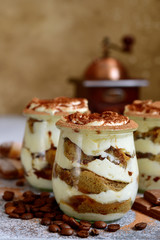Traditional italian creamy dessert with mascarpone, biscuit and coffee in a vintage jars.
