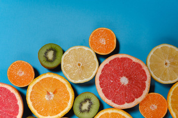 Tropical summer mix grapefruit, orange, mandarin, kiwi, lemon. Citrus fruits vegan vitamin mix flat lay on blue background, healthy vegetarian organic food, antioxidant detox diet.
