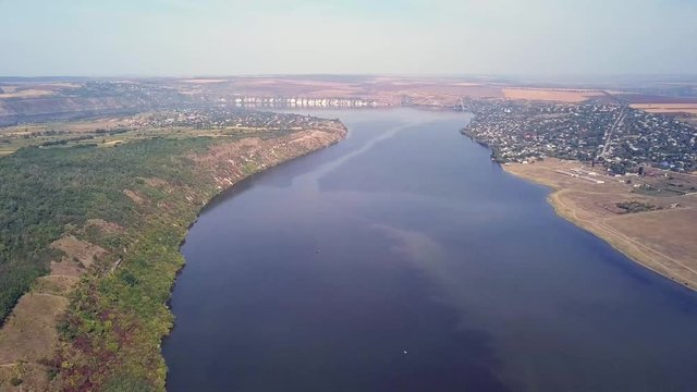 Top view of Dnestr (Dniester) river in autumn. River surrounds yellow field and green forest. Moldova republic of.