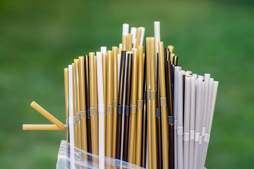 Plastic straws in a plastic bag on grass background. Plastic pollution, environmental waste. Say no to plastic straws. Save our green planet