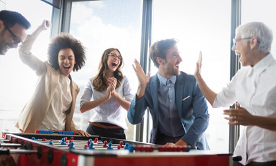Multicultural business people celebrating win while playing table football