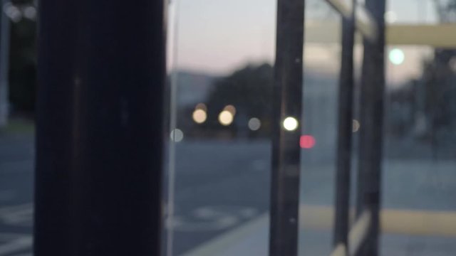 Urban city defocused vehicle ights at dusk through bus stop windows