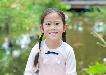 Beautiful little Asian child girl in the nature garden.