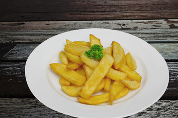 French fries with salt on white plate on vintage table.