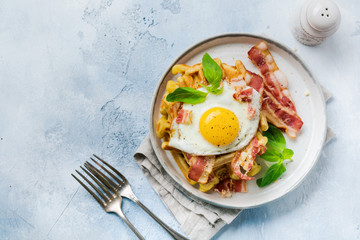 Cheese Waffles with fried bacon, egg and parmesan cheese with spices and basil for breakfast on light old concrete background. Top view.