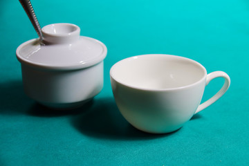 Porcelain cup and sugar container against a blue colored background