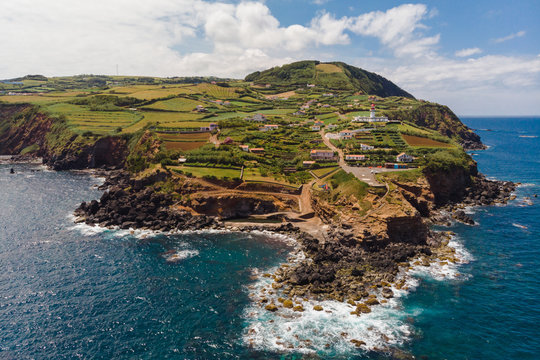 Aerial view of the easternmost part of Sao Jorge Island: "Ponta do Topo" and lighthouse (Farol) with the atlantic ocean against blue sky