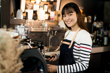 Young owner or pretty barista making coffee at the coffee shop.