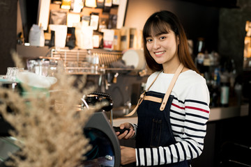 Young owner or pretty barista making coffee at the coffee shop.