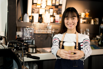Young asian women barista hold coffee cup serving a client at the coffee shop,start up small business owner food and drink concept..