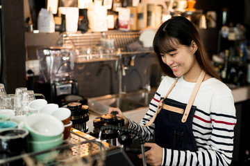 Young owner or pretty barista making coffee at the coffee shop.