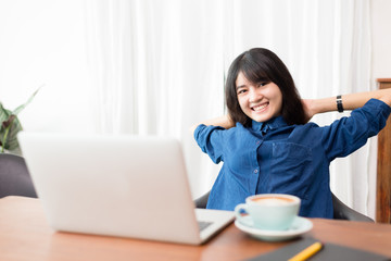 Young woman or student using laptop sitting at coffee shop. Happy girl working online or studying and using notebook. Freelance business concept.