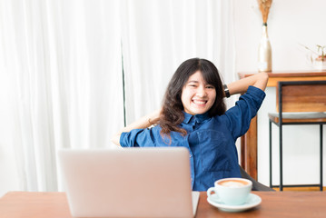 Young woman or student using laptop sitting at coffee shop. Happy girl working online or studying and using notebook. Freelance business concept.