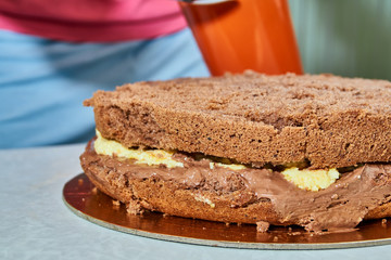 Cooking homemade cake. Two layer sponge cake with of chocolate cream and a layer of orange cream on a light background. Close-up