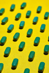 medicinal capsules, pills and tablets on yellow background. nutrition supplements, green vitamin pills. pills pattern on a yellow background
