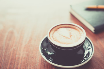 Coffee cup on wooden table and notebooks.