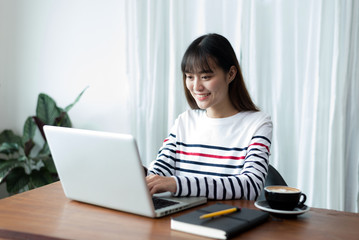 Young woman or student using laptop sitting at coffee shop. Happy girl working online or studying and using notebook. Freelance business concept.