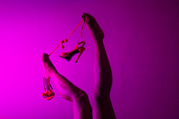 Red or orange high heels shoes and sexy black woman legs on pink background.