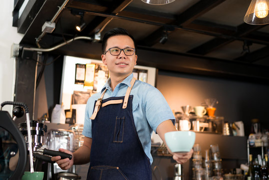 Young asian men barista hold coffee cup serving a client at the coffee shop,start up small business owner food and drink concept..