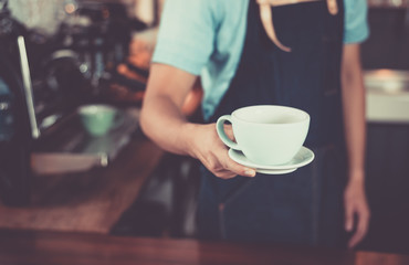Young asian men barista hold coffee cup serving a client at the coffee shop,start up small business owner food and drink concept..