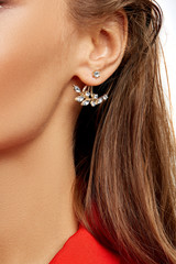 Cropped close-up shot of female ear with luxury golden jacket-earring with sparkling crystals made in the form of flower with diamonds. 