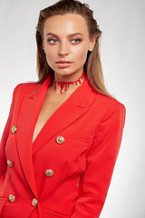 Three quarter cropped shot of a pretty and stylish young European woman with long straight chestnut hair dressed in fire-red jacket with golden buttons and pockets. 