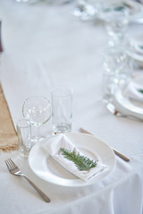 Wedding decorations. White plates on a white tablecloth. Natural style wedding