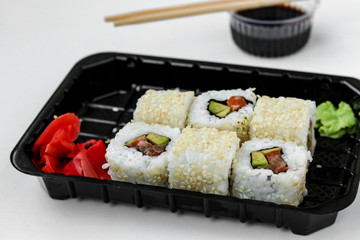 Syake rolls in a set of 6 pieces in a black box, with ginger, wasabi and soy sauce, fast food, horizontal orientation