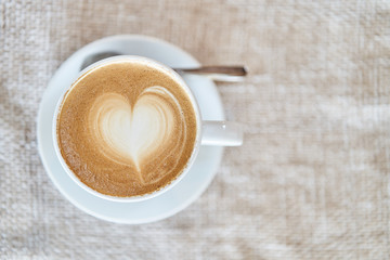 Top view of a mug with latte on a brown background. Coffee with a heart shape