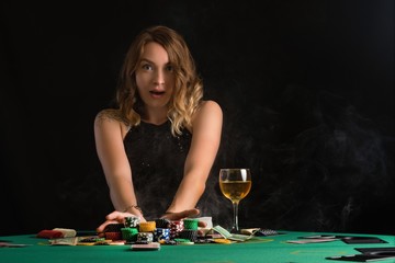 A woman in an evening dress plays in a casino. Woman puts a lot of chips. Gaming business and entertainment. Poker.