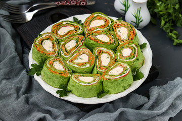 Lavash roll with crab sticks, spinach, parsley and carrots in Korean style on a plate against a dark background, horizontal orientation