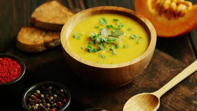 Fresh pumpkin soup in bowl on chopping board