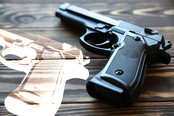 Obraz premium Gun with a shadow lying on wooden background. Legalization of weapon.