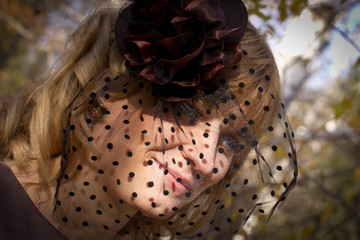beautiful blonde girl in a hat with a veil in autumn