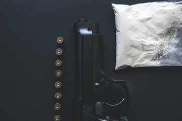 Gun with bullets lying on the table. Criminal problems. Drugs and on black background. Illegal selling.