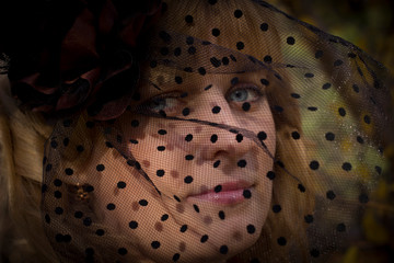 beautiful blonde girl in a hat with a veil in autumn